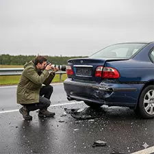 Gutachter fotografiert beschädigtes Auto nach Verkehrsunfall